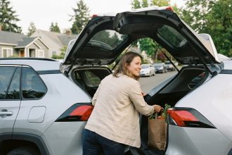 Femme chargeant ses courses dans un SUV compact dans une rue résidentielle, illustrant l'utilisation quotidienne d'un SUV compact en ville