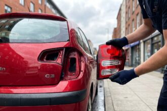 Feu arrière Citroën C3 partiellement démonté par un mécanicien dans une rue urbaine