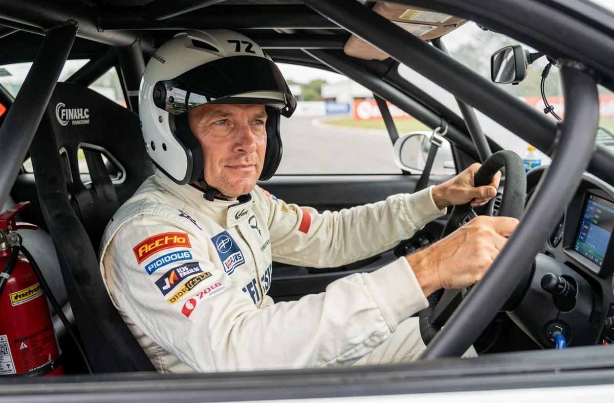 Pilote amateur en tenue de course installé dans l'habitacle d'une voiture de piste préparée pour le circuit