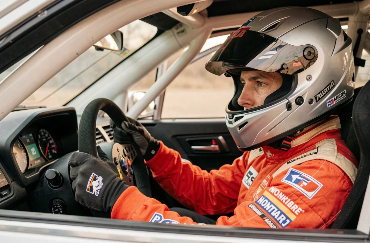 Pilote de rallye en combinaison Subaru aux commandes d'un cockpit de voiture de rallye hybride moderne