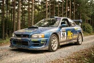 Subaru Impreza WRC en livrée bleue iconique sur une route de service en gravier entourée de forêt de pins