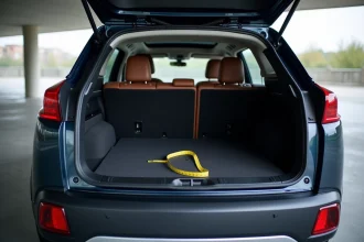 Vue arrière du coffre ouvert d'un Peugeot 3008 Phase 2 dans un parking, illustrant le volume de chargement disponible